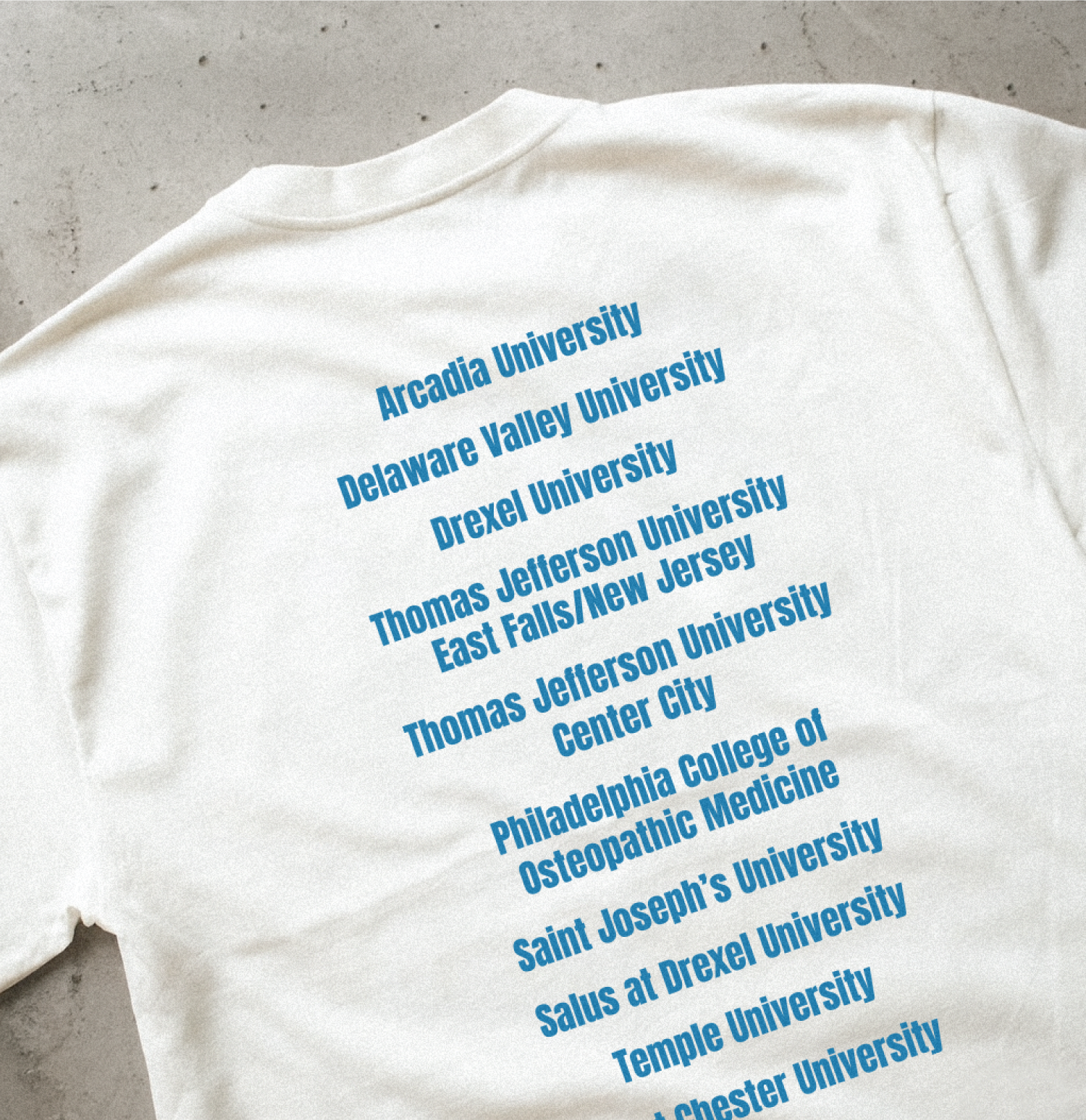 Back of white event shirt featuring blue printed list of participating universities, showing which tshirt print is best for multi-campus charity events.