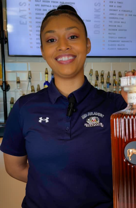 Restaurant staff member wearing a branded navy polo shirt, showcasing how custom restaurant staff uniforms contribute to restaurant branding through uniforms and transform uniforms into wearable brand merchandise.